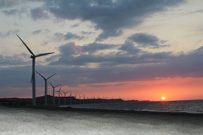 A view of the windmills by the bay during sunset.