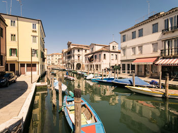 Boats moored in canal by buildings against sky in city