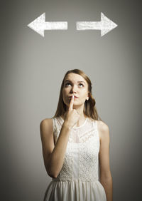 Portrait of a young woman looking away against wall