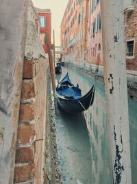 Boats moored in canal amidst city