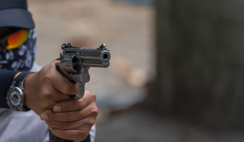 Midsection of man pointing gun outdoors