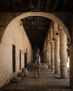 Full length portrait of woman standing against building