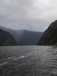 Scenic view of sea and mountains against cloudy sky