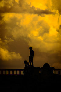 Low angle view of silhouette man standing against orange sky