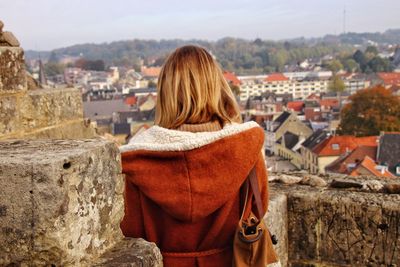 Rear view of woman standing on retaining wall