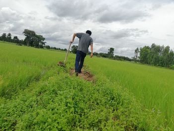 Rear view of man on field against sky