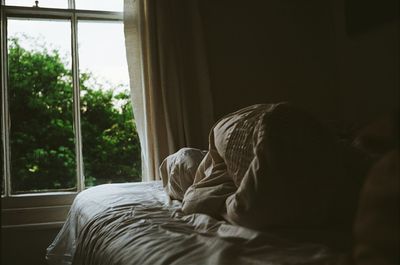 Rear view of woman relaxing on bed