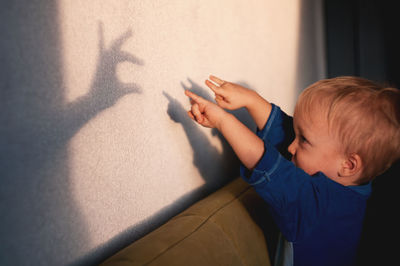 Cute boy gesturing against wall at home
