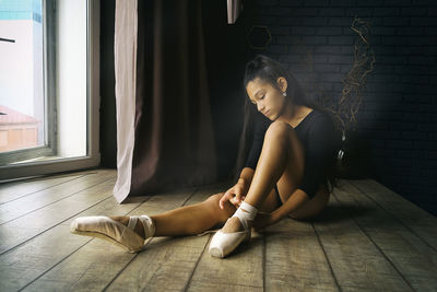 A young gentle and thoughtful ballerina poses in the interior and at the window