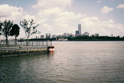 Scenic view of river by buildings against sky