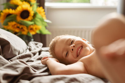 Portrait of smiling young woman lying on bed at home