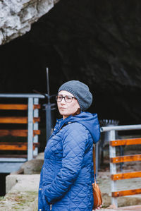 Woman wearing warm clothing while standing against rock formation