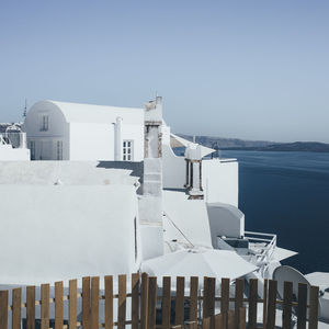 Built structure by sea against clear blue sky