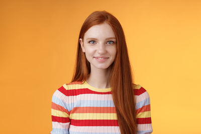 Portrait of smiling young woman against yellow background