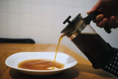 Close-up of hand pouring coffee cup