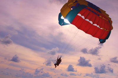 View of person parasailing against cloudy sky at dusk