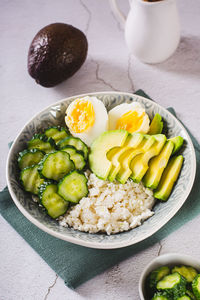 Fresh cottage cheese, avocado, cucumber and boiled egg in a plate vertical view