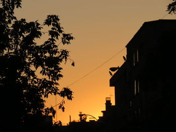 Silhouette built structures against clear sky at sunset