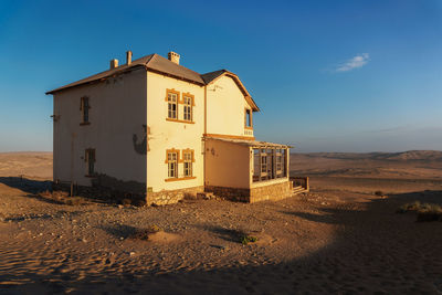 House on beach by building against sky