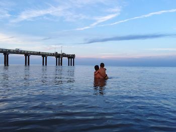 Man with son in sea against sky