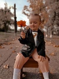Cute girl sitting with flower on stool