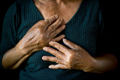 Midsection of senior woman with hands on chest