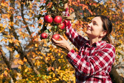 Side view of young woman holding apple