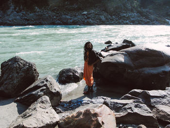 Woman standing on rocks at sea shore