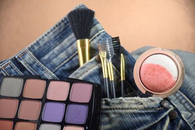 High angle view of make-up equipment and jeans on table