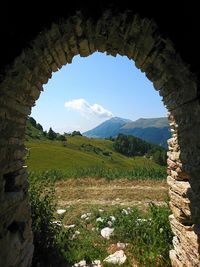 Scenic view of landscape against sky seen through arch