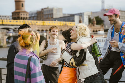 Happy non-binary friends embracing each other in city