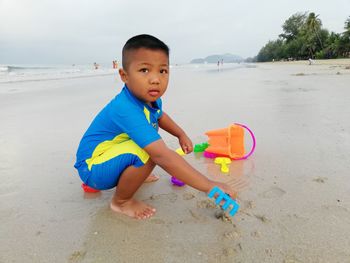 Portrait of cute boy playing with toy at sandy beach