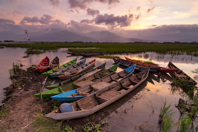 Panoramic view of boats moored at beach against sky during sunset