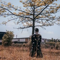 Man standing by tree on field against sky