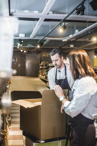 Owners unpacking cardboard box while standing in store