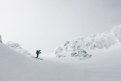 Young man skiing on snowcapped mountain against sky