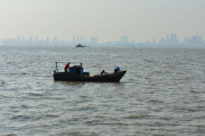 Ship sailing in sea against sky in city