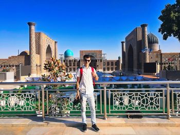 Man standing against buildings against clear blue sky