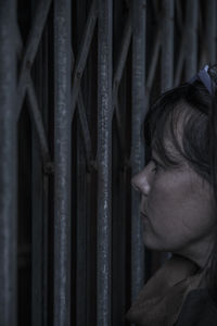 Profile view of thoughtful woman standing by metal gate