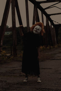 Young woman in mask standing on bridge