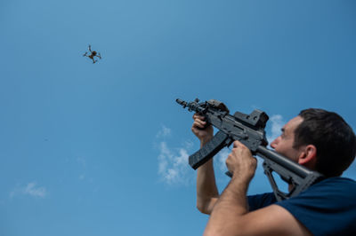 Low angle view of man holding key against sky