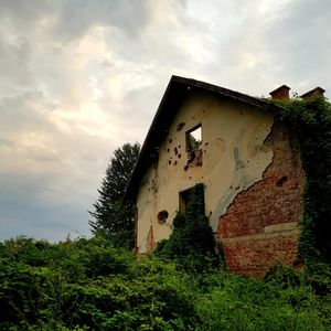 Low angle view of old abandoned house on field against sky