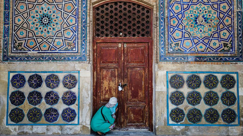 Rear view of woman against closed door of building