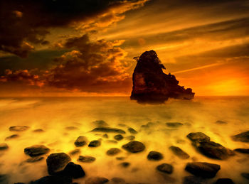 Scenic view of rocks in sea against sky during sunset