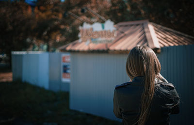 Rear view of woman standing outside house