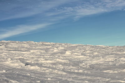 A hill covered with snow, against a background of blue sky.