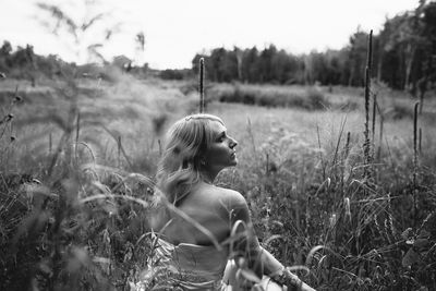 Thoughtful young woman sitting on grassy field