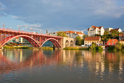 Bridge over river by buildings against sky in city