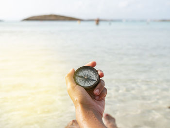 Midsection of person holding umbrella against sea