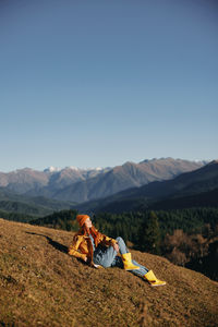 Rear view of woman sitting on mountain